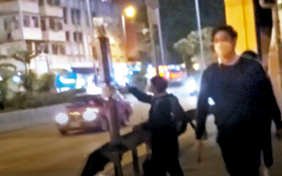 ◆2月14日晚，李盈姿（左一）在九龍灣的不同路段貼街招後快速離去。讀者供圖