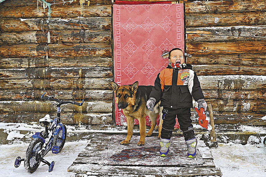 ◆新疆阿勒泰地區禾木村的小朋友其力格爾在小木屋前玩耍。