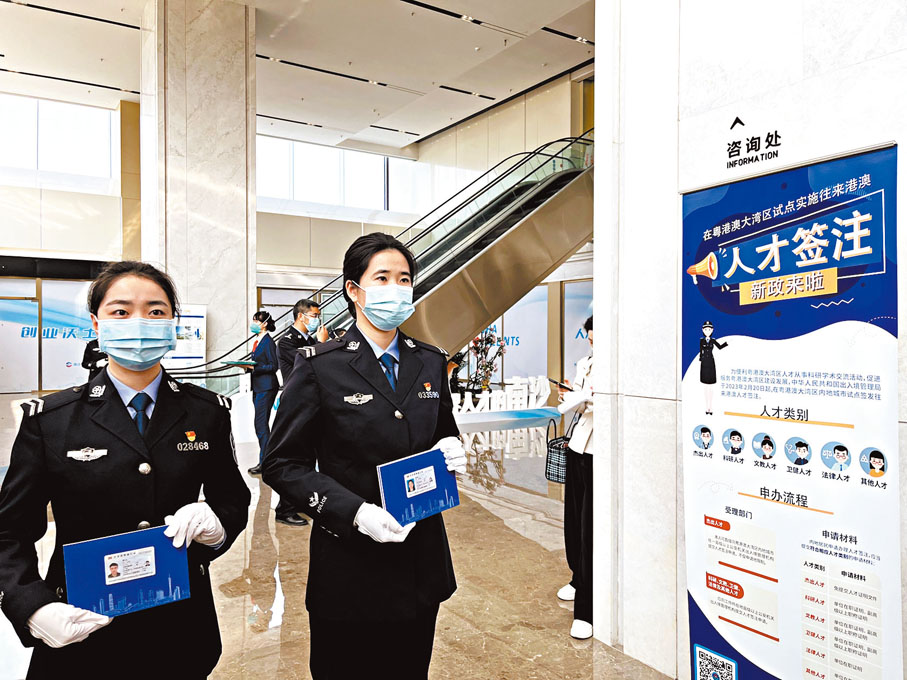 ◆首發儀式在廣州移民服務中心南沙分中心舉行。圖為工作人員在國際人才港一樓大堂的辦證指南展板前展示卡片樣板。香港文匯報廣州傳真