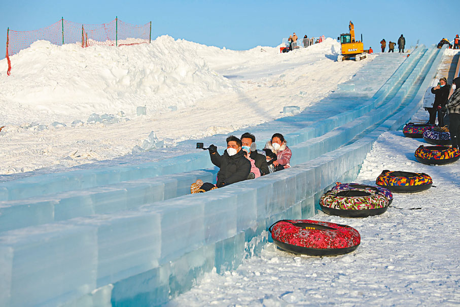 ◆來自兩個家庭的遊客在瀋陽棋盤山冰雪大世界中感受冰滑梯。