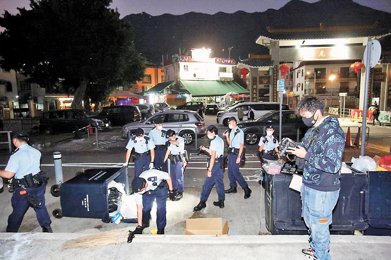 ◆機動部隊警員在村內的垃圾站搜索證物。香港文匯報記者鄺福強  攝