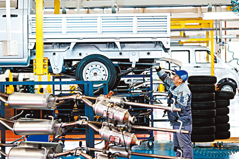 ◆ 今年1-2月份，內地工業和服務業生產雙雙回升。圖為工人在貴州省遵義市一家整車生產企業安裝車胎。 中通社