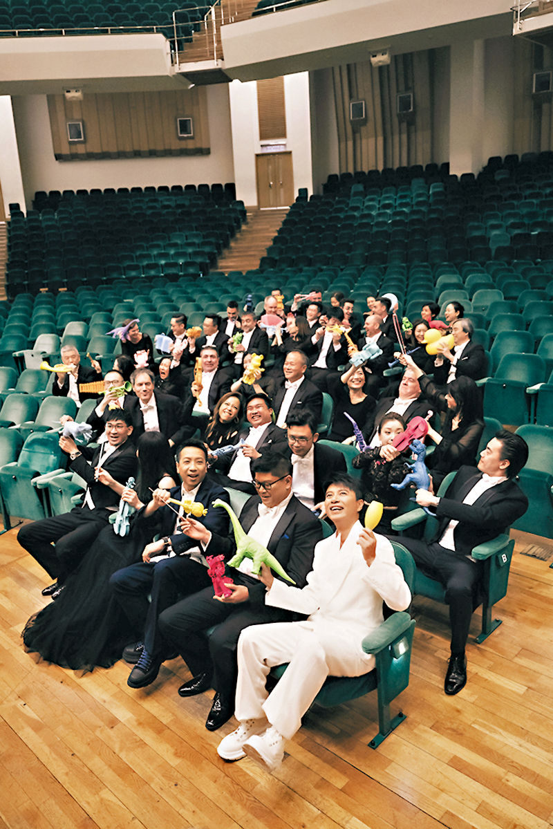 ◆李克勤與管弦樂團一眾成員，像小朋友一樣拿玩具你打我鬧。