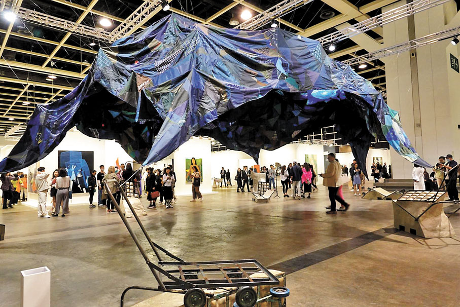 【林嵐《推車派對》】《推車派對》由14米的拼布和六個手推車座位組成，以這個城市丟棄的廢料製作。與香港紡織業傳統業者緊密合作的過程，喚起了香港藝術家林嵐對勞工及消費主義的思考。通過轉化回收材料的本質，她創造出令觀眾可以聚集的庇護所，一起坐下，並得到一刻喘息。