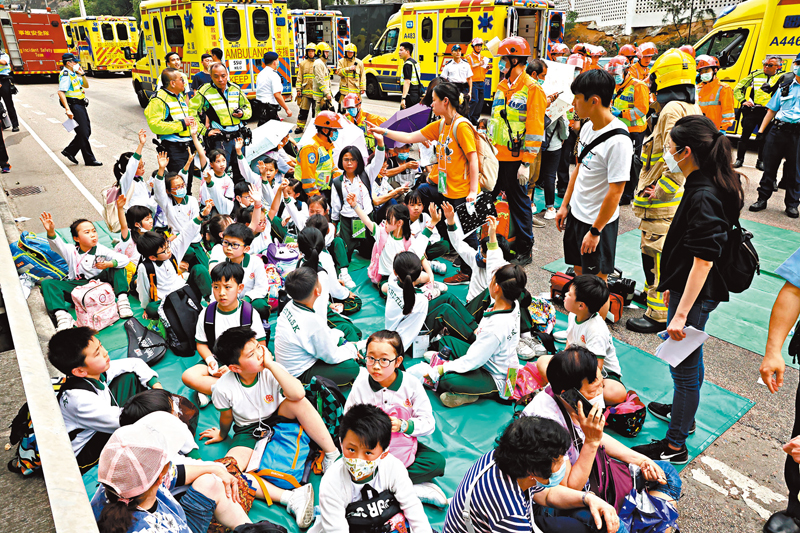 ◆車禍中沒有受傷的學童在現場等候老師安排返回學校。 香港文匯報記者劉友光  攝