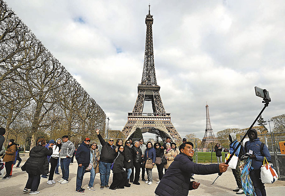 ◆遊客在法國巴黎埃菲爾鐵塔附近拍照留念。