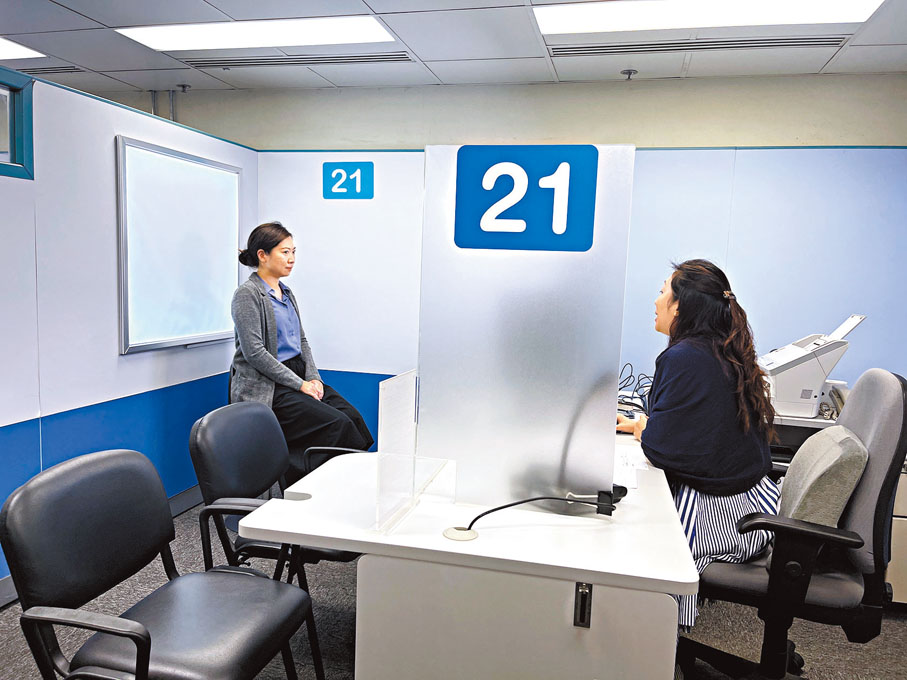 ◆李玉蓮幫助市民影身份證相片。香港文匯報記者唐文  攝