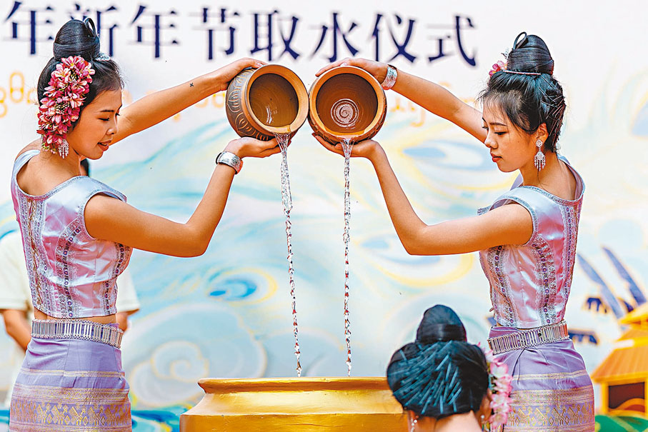 ◆在景洪市瀾滄江畔，兩名傣族少女在取水儀式上灌「聖水」。