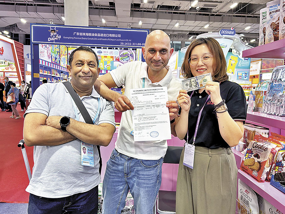 ◆ 兩名南非採購商在廣交會現場和廣東上益食品有限公司當場簽約，下訂10個貨櫃糖果。圖為雙方展示簽約單，並象徵性展示交易資金。