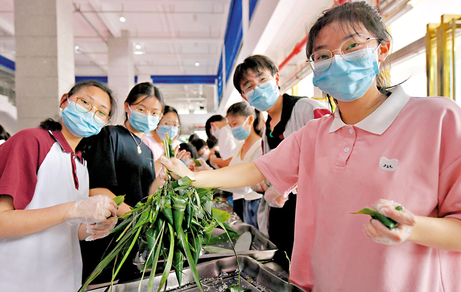 ◆不少學校組織暖心舉措護航高考活動，幫助學生緩解應考壓力。圖為4日，湖北省宣恩縣一中的高三學生在展示包好的糉子。新華社