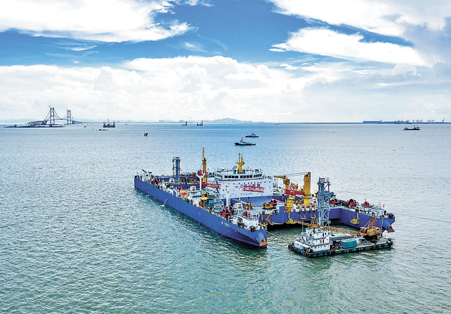 ◆ 深中通道海底隧道全線6月11日順利合龍。圖為6月9日拍攝的「一航津安1」號沉管運輸安裝一體船在沉放安裝E23管節和最終接頭，背後是建設中的深中通道伶仃洋大橋。 新華社