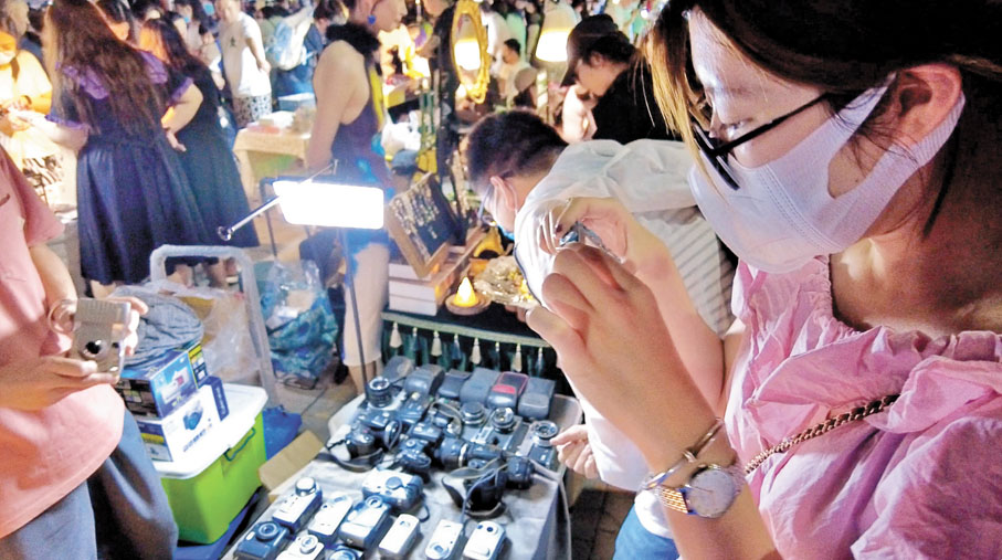 ◆近日，一位顧客在北京潘家園二手相機攤販試用CCD相機。   中通社