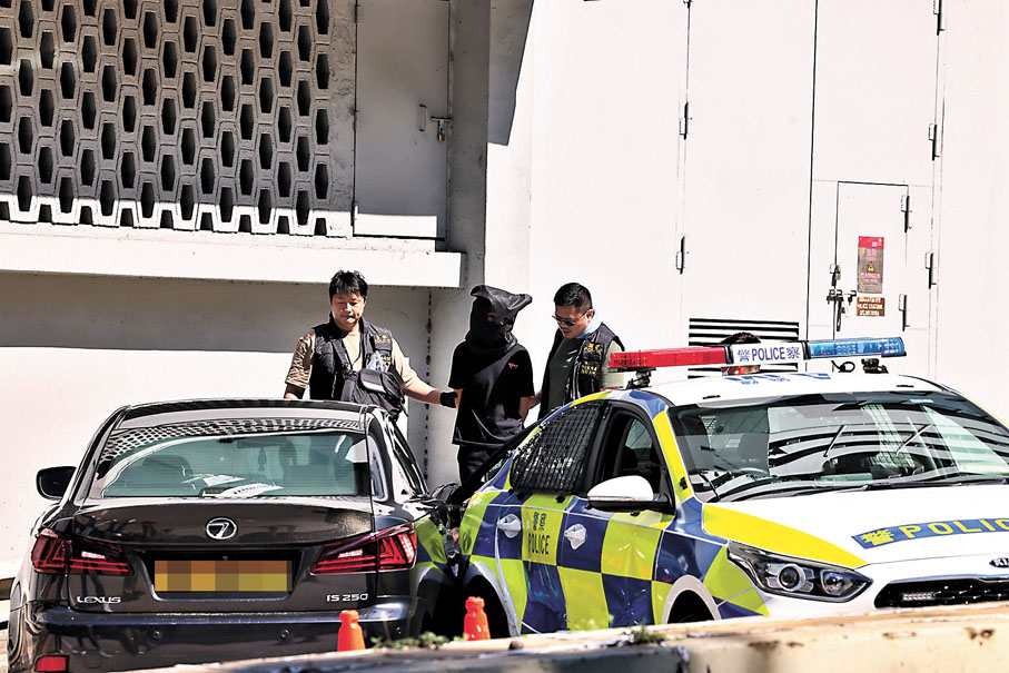 ◆案發當日影子車司機被黑布蒙頭及鎖上手銬在現場接受調查。資料圖片