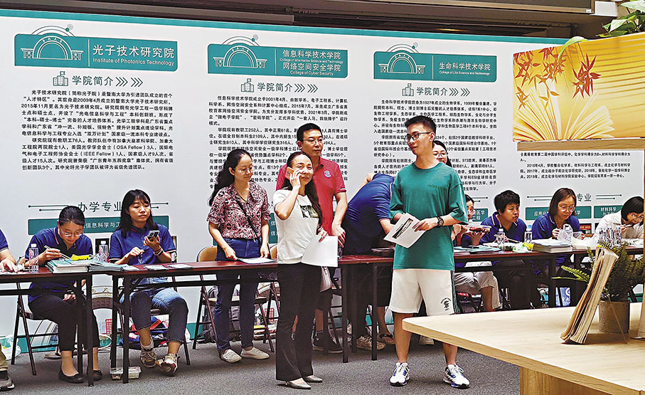 ◆24日，暨南大學校園開放日中，一名家長和學生在了解不同學院的招生情況。 香港文匯報記者盧靜怡  攝