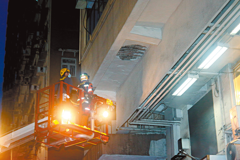 ◆ 7月19日，在筲箕灣道33號至35號麗灣大廈發生墜石屎傷人。圖為消防員架起升降台檢查大廈石屎剝落位置。 資料圖片