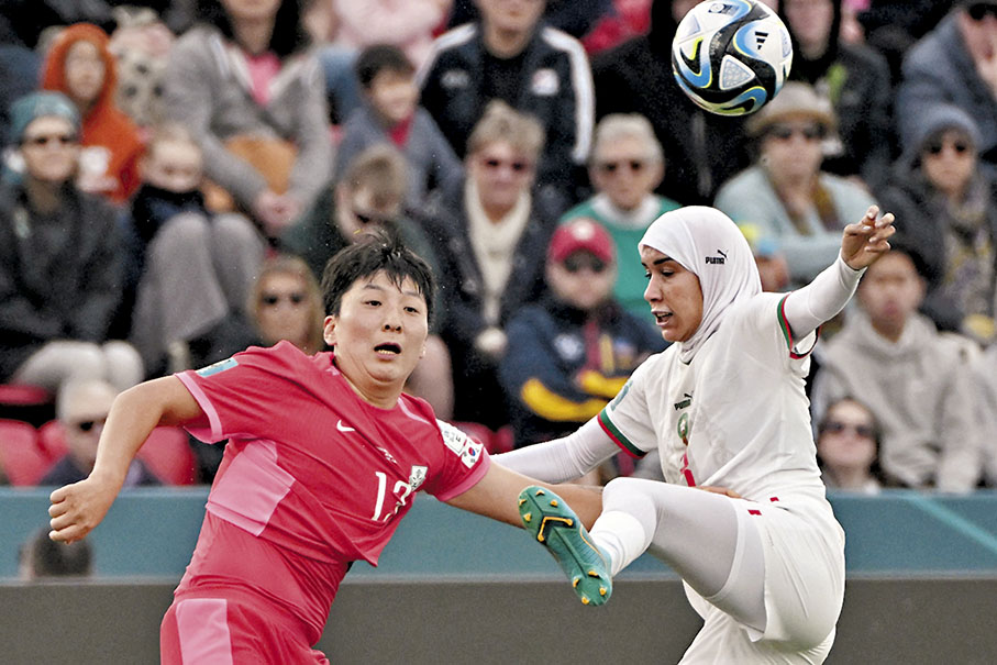 ◆ 國際足協近10年前解除足球員不得穿戴希賈布頭巾的禁令，25歲的摩洛哥隊球員賓絲娜(右)昨天在場上戴着穆斯林希賈布頭巾上陣，創下女足世盃首例。  法新社