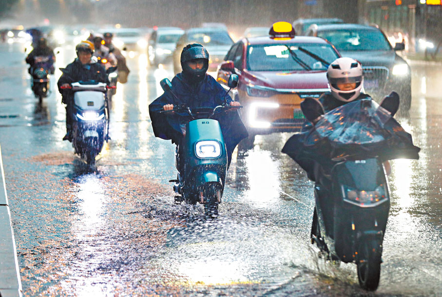 ◆7月31日，北京強降雨持續，市民在雨中騎車出行。北京市氣象台當日10時發布分區域暴雨紅色預警信號。 中新社