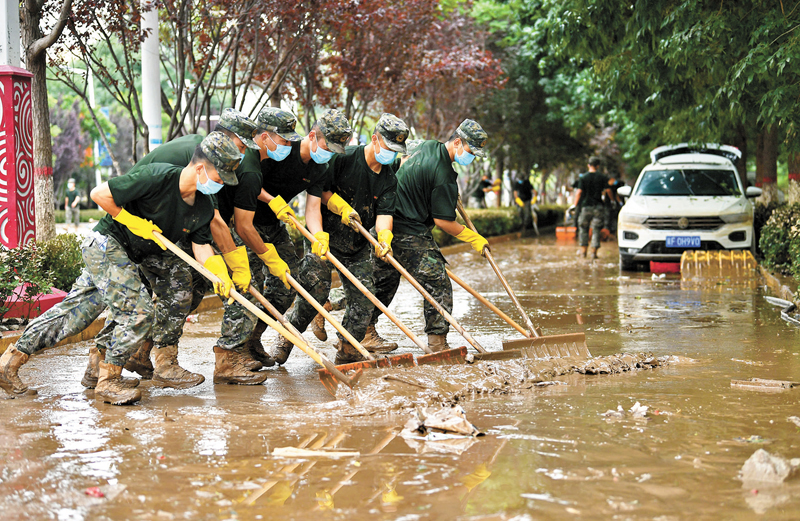 ◆在涿州市騰飛大街和朝陽路交口，武警河北總隊的官兵正在清理路面上的淤泥和雜物。 中新社
