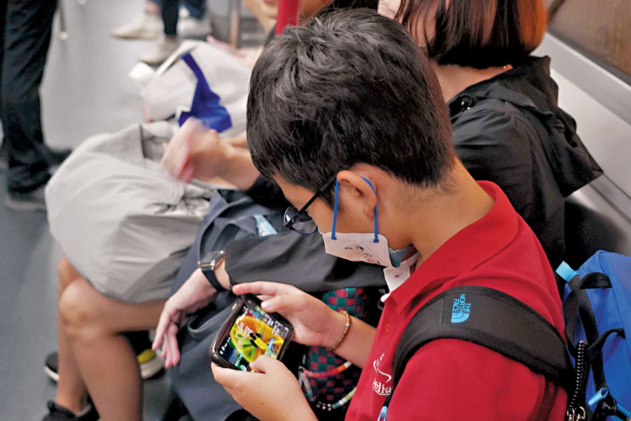 ◆青少年面對網絡罪惡威脅日益嚴峻，今年上半年有1,115宗網絡罪案的受害人是學生。圖為青年在港鐵玩手機網絡遊戲。 資料圖片