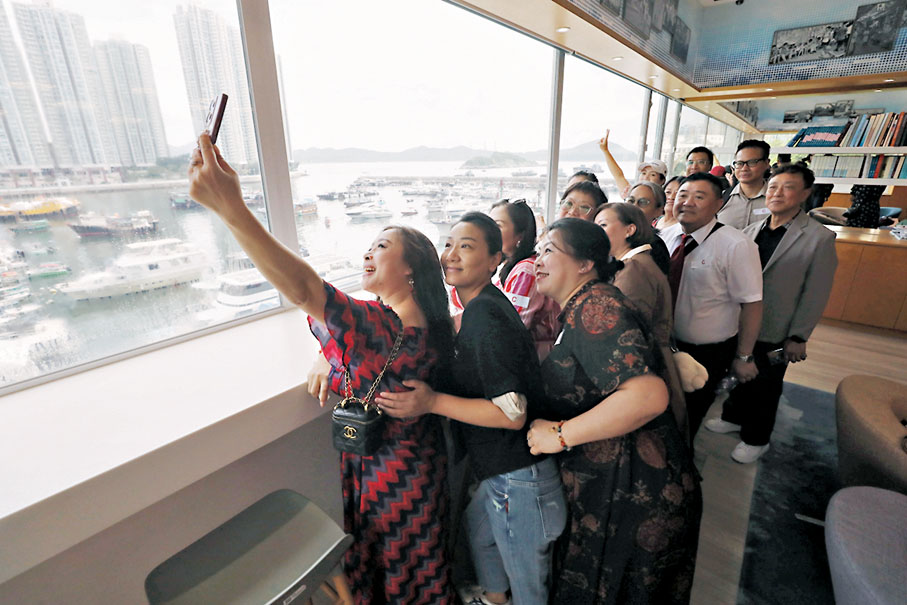 ◆讀者在大文集團工作室合影，窗外是香港仔避風塘景色。