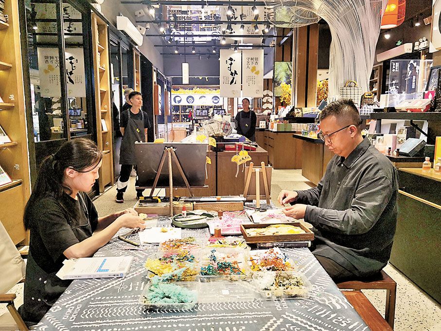 ◆遊客在「銀杏樹下的守藝人」文創店體驗貼畫製作。香港文匯報記者張帆 攝