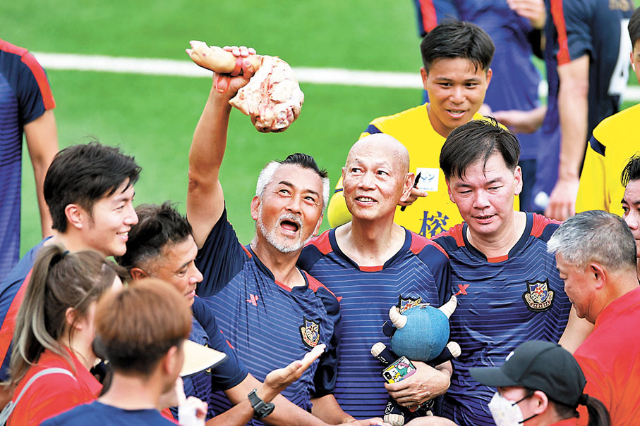 ◆香港明星隊球員舉起作為比賽獎品的豬蹄。