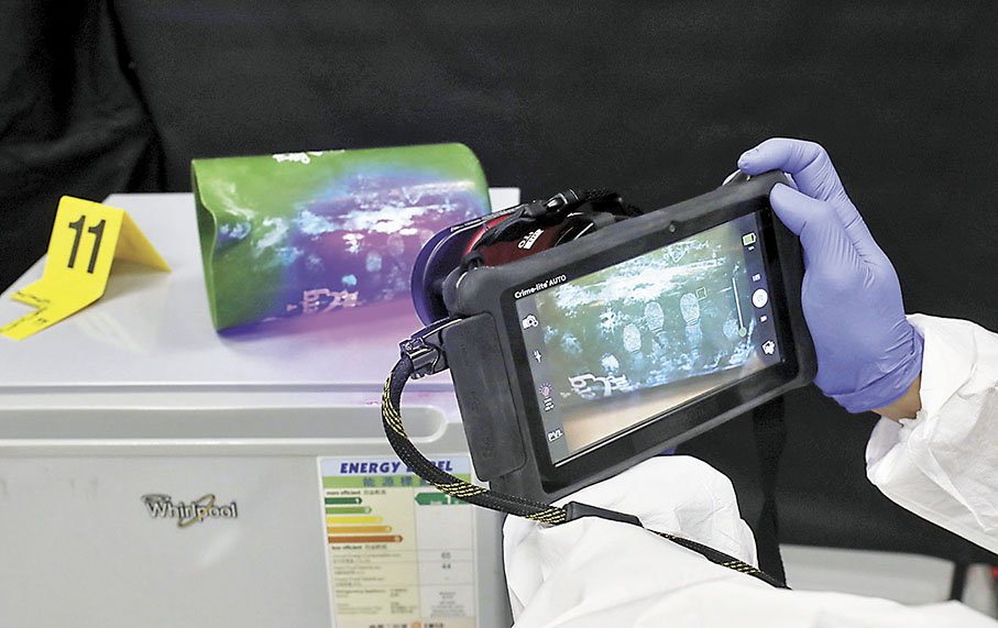 ◆鑑證科人員在模擬罪案現場，示範如何使用便攜式儀器檢驗指紋。 香港文匯報記者郭木又 攝