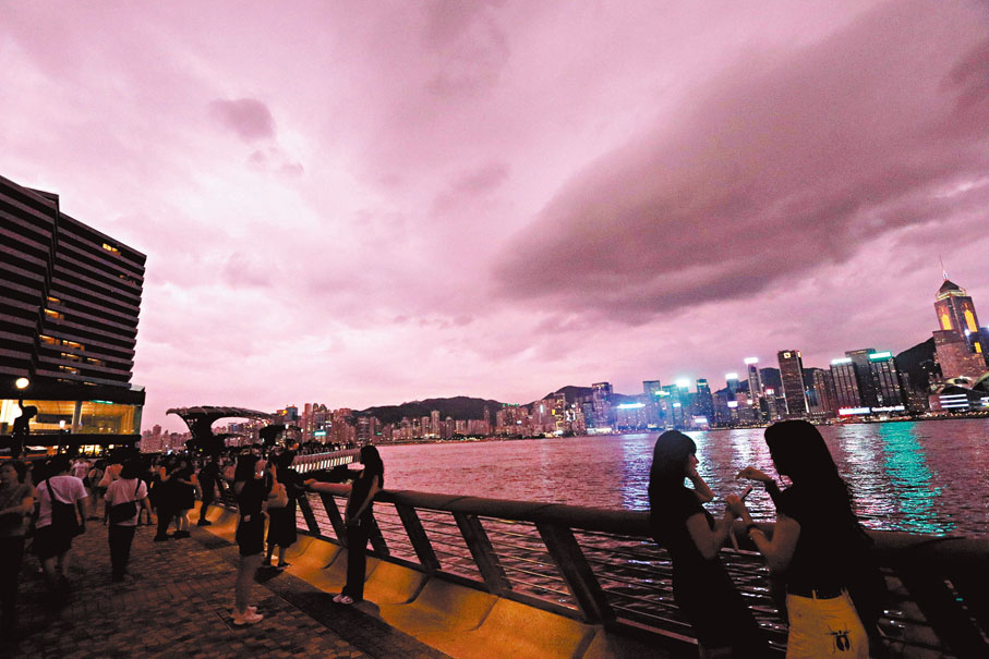 ◆趁超強颱風「蘇拉」未到之際，市民和遊客在尖沙咀海旁打卡，維港上空烏雲密布。香港文匯報記者北山彥  攝