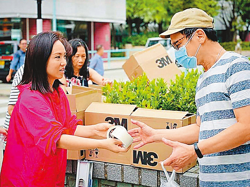 ◆ 新民黨立法會議員陳家珮（左）落區向居民派貼窗膠紙。