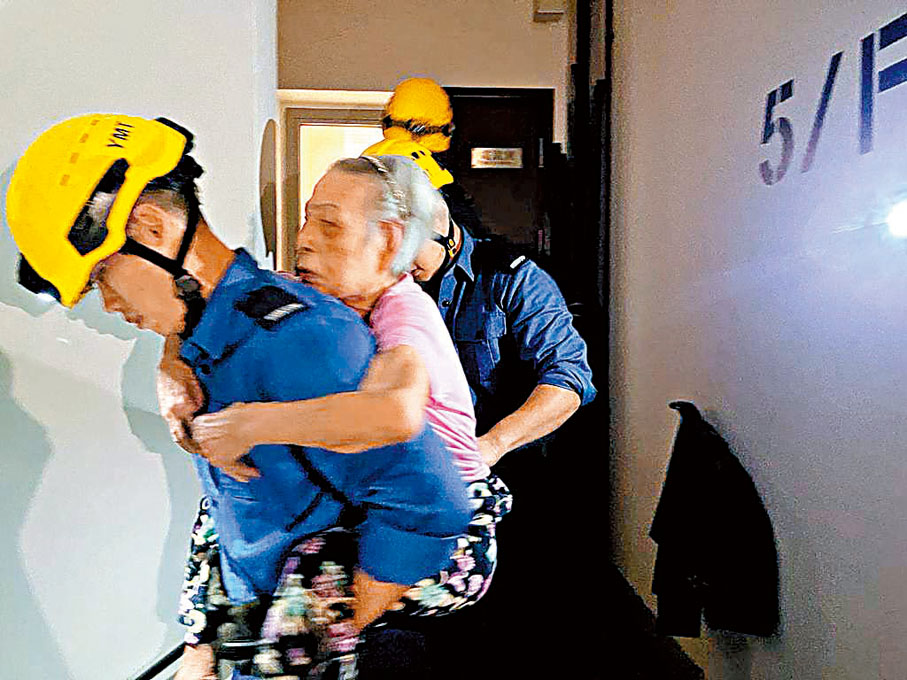 ◆消防員將行動不便長者揹落樓。 香港文匯報記者郭倩  攝