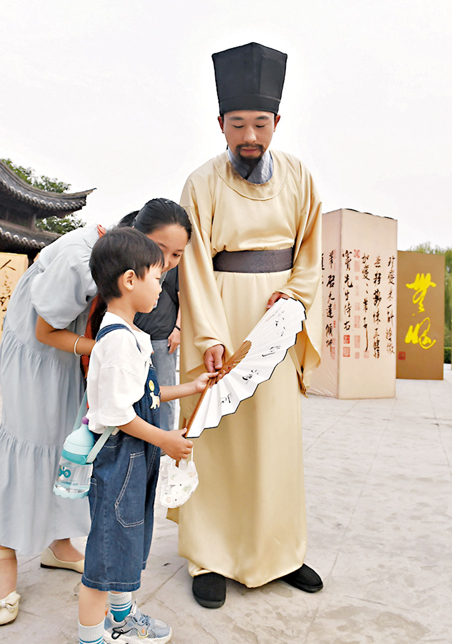 ◆身穿古裝的工作人員在中國翰園碑林景區與小遊客互動。