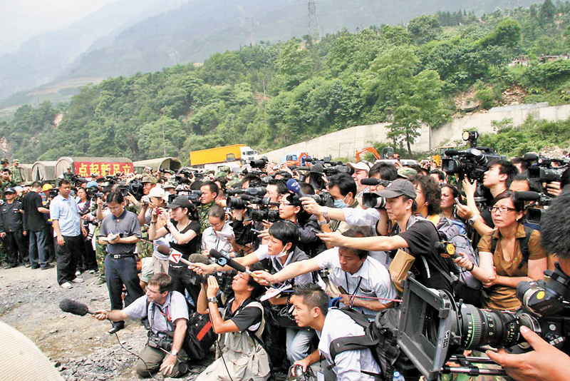 ◆2008年5月24日，溫家寶在汶川地震的震中映秀鎮接受媒體採訪，香港文匯報記者（右二，戴深灰帽者）與大批中外記者在緊張工作。 資料圖片