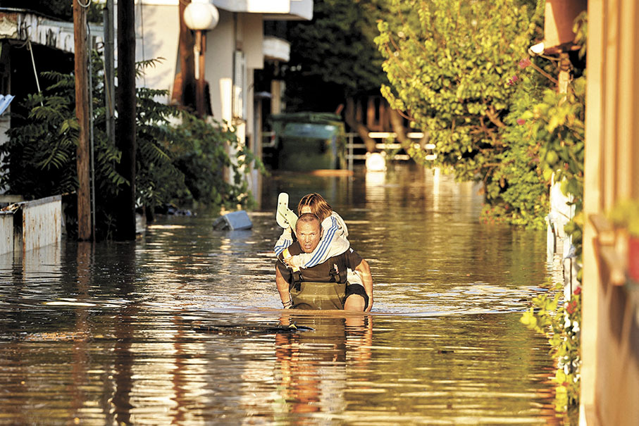 ◆希臘拉里薩河水氾濫，消防員救起一名被困兒童。 路透社