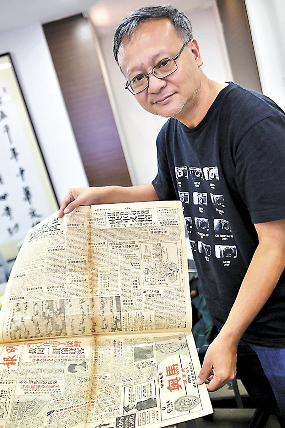 ◆鄺啟東展示他收藏的金庸相關報刊。小凡  攝