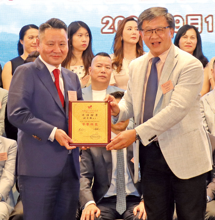 ◆何君堯（右）頒發敦請書予平海同鄉會榮譽總監邱來強（左）。