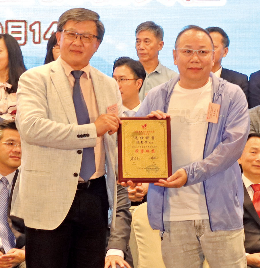 ◆何君堯（左）頒發敦請書予平海同鄉會榮譽總監陳惠榮（右）。