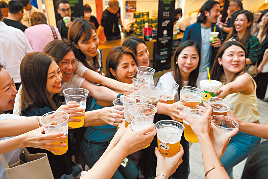 ◆ 約1,750間食肆國慶當日推出七折優惠或特別優惠價,市民「飲得杯落」。圖為市民在夜市購買飲品後碰杯。 資料圖片