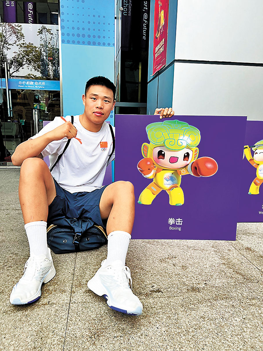 ◆年輕拳手韓雪振在亞運選手村與拳擊運動員造型吉祥物琮琮合影。香港文匯報河南傳真