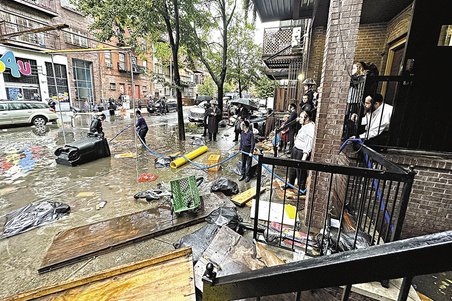 ◆市政工人試圖清理排水口，疏導積水。 美聯社