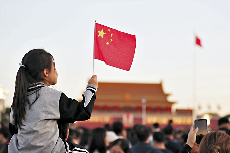 ◆10月1日清晨，小朋友手持國旗在天安門廣場上靜靜觀看五星紅旗冉冉升起。  中新社