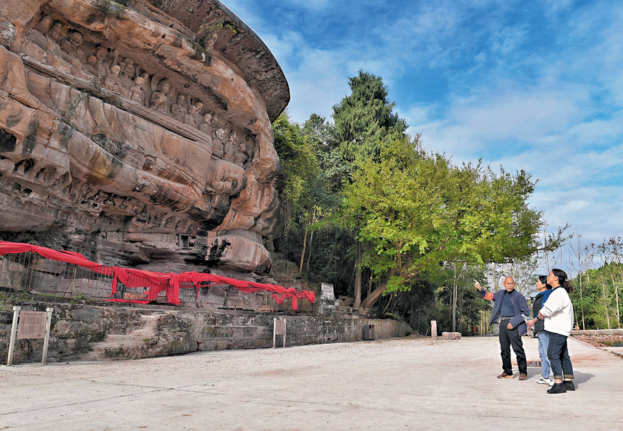 ◆吳忠富（左一）在向遊客介紹臥佛。