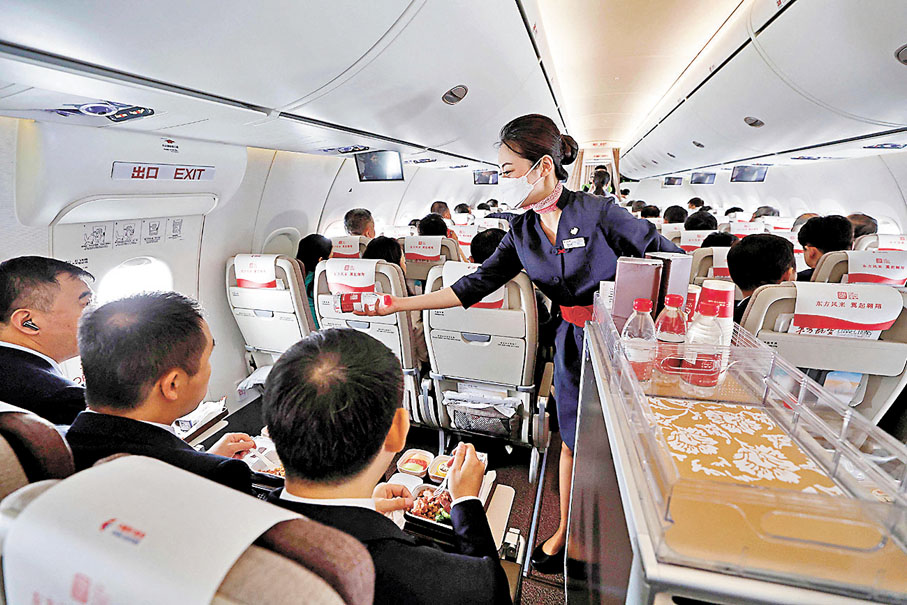 ◆2023年5月28日，C919全球首次商業載客飛行。圖為乘務員在飛行途中為旅客提供餐飲。 資料圖片