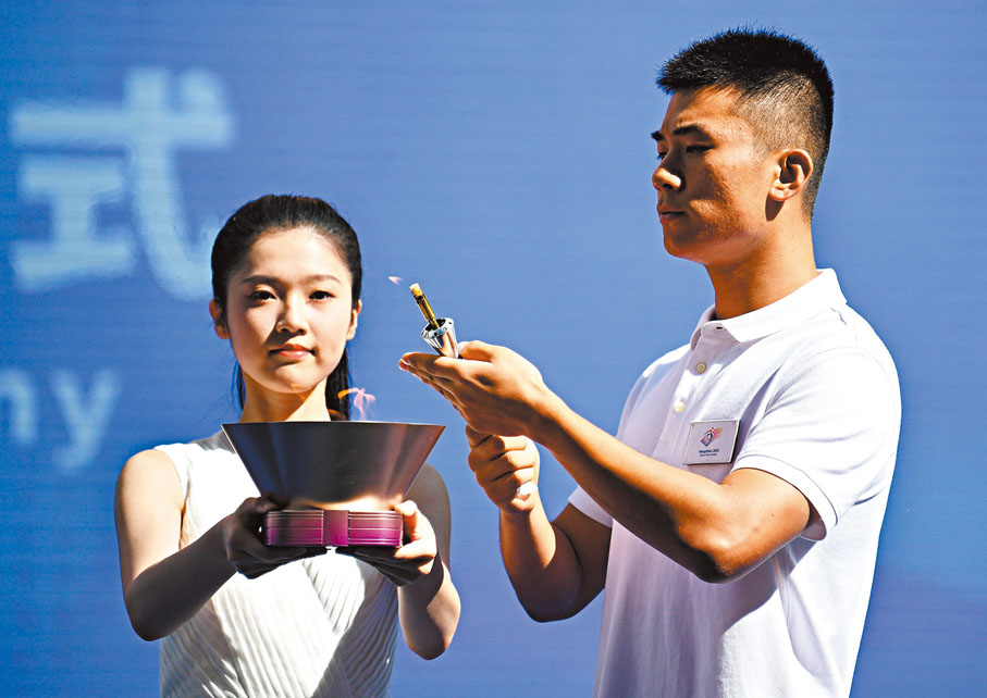 ◆火種護衛（右）從火種盒引火。 新華社