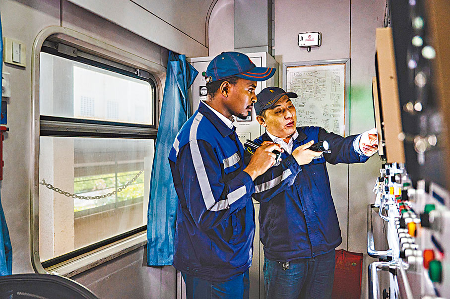 ◆多年來，中國「師傅」與肯尼亞「徒弟」因蒙內鐵路結下了深厚情誼。圖為在肯尼亞內羅畢，吳同明（右）與學員基魯姆瓦在車輛運用車間檢查發電車。 資料圖片