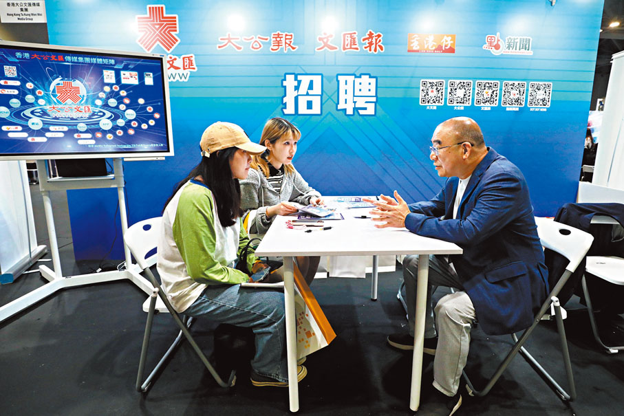 ◆香港文匯報總編輯吳明（右）昨日在招聘會現場解答應徵者的查詢。香港文匯報記者郭木又 攝