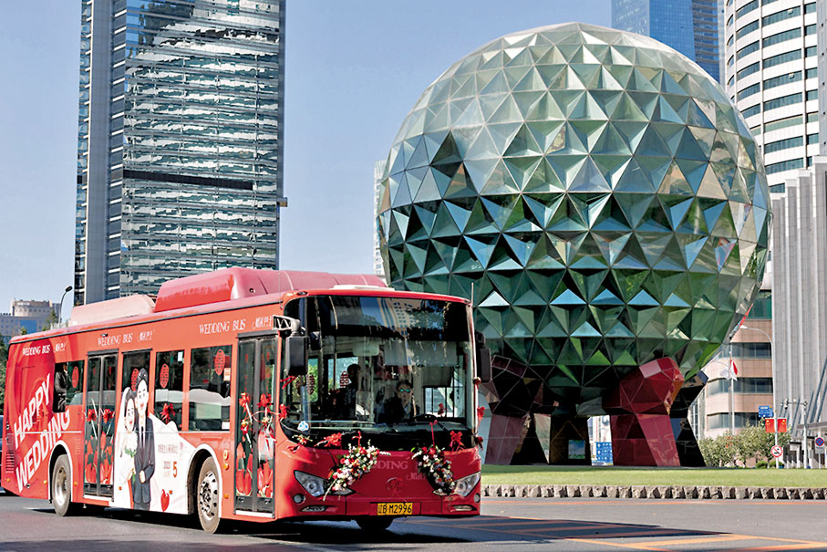 ◆「婚禮巴士」駛過大連地標建築友好廣場水晶球。 