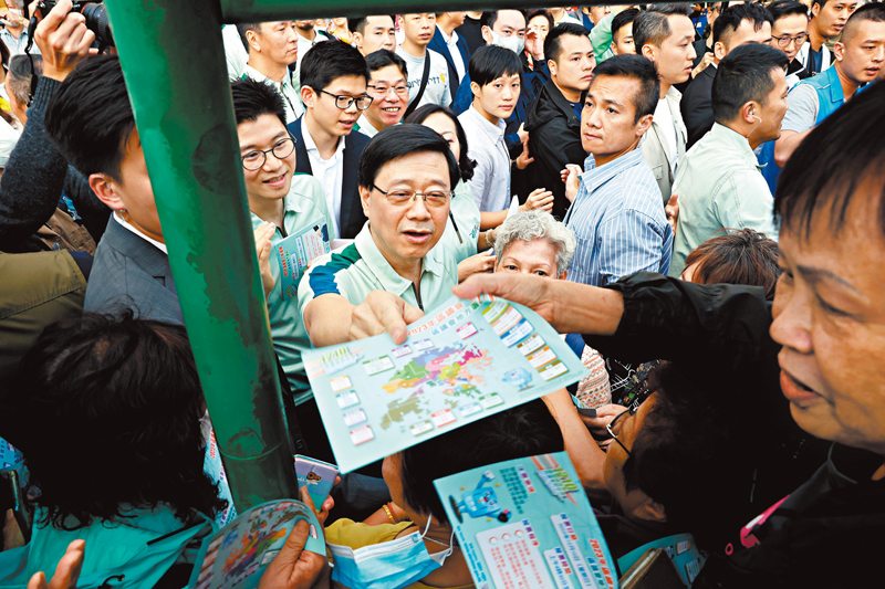 ◆李家超落區，在大批熱情居民簇擁中派發區選單張。 香港文匯報記者劉友光  攝