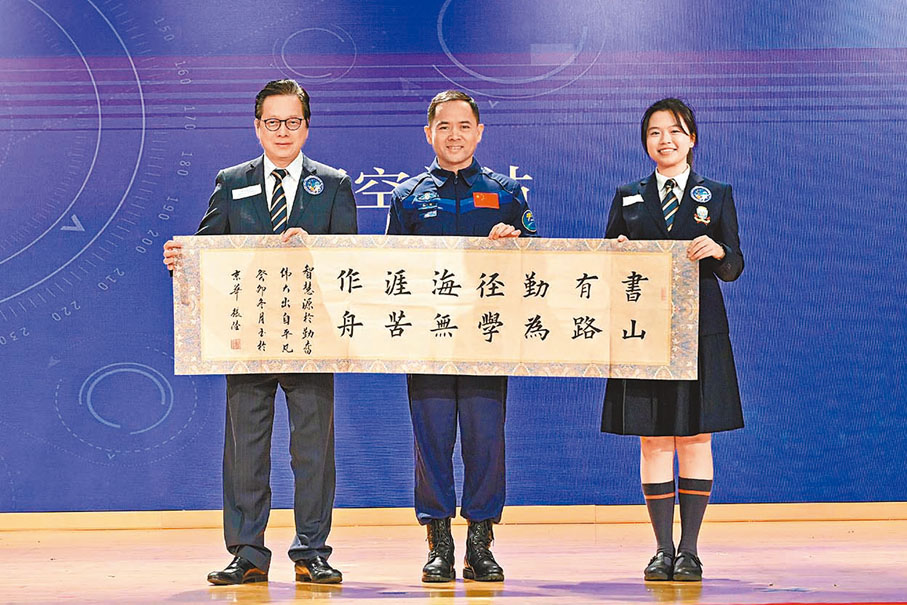 ◆張陸（中）到浸大附屬王錦輝中小學訪問時，特別與該校總校長陳偉佳一同展示其為學校以歐楷筆法撰寫的書法作品。