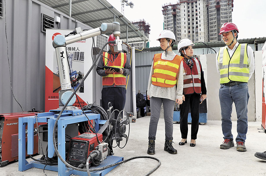 ◆何永賢（右三）視察工地建築機械人。 香港文匯報記者郭木又  攝