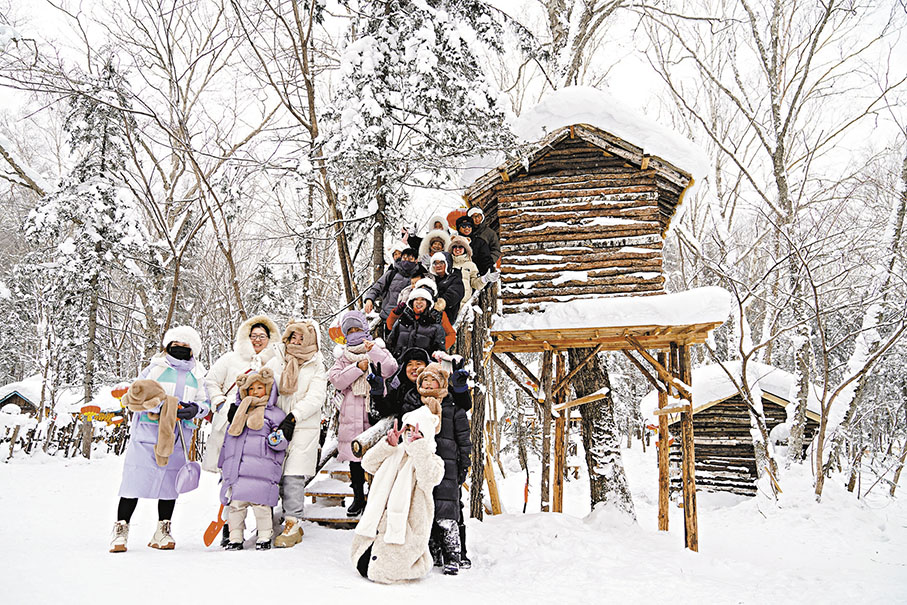 ◆圖為來自浙江的20餘名遊客與雪中小木屋合影。    中新社